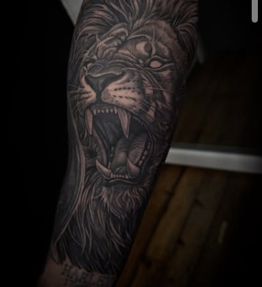 Black and grey realism tattoo of a roaring lion head