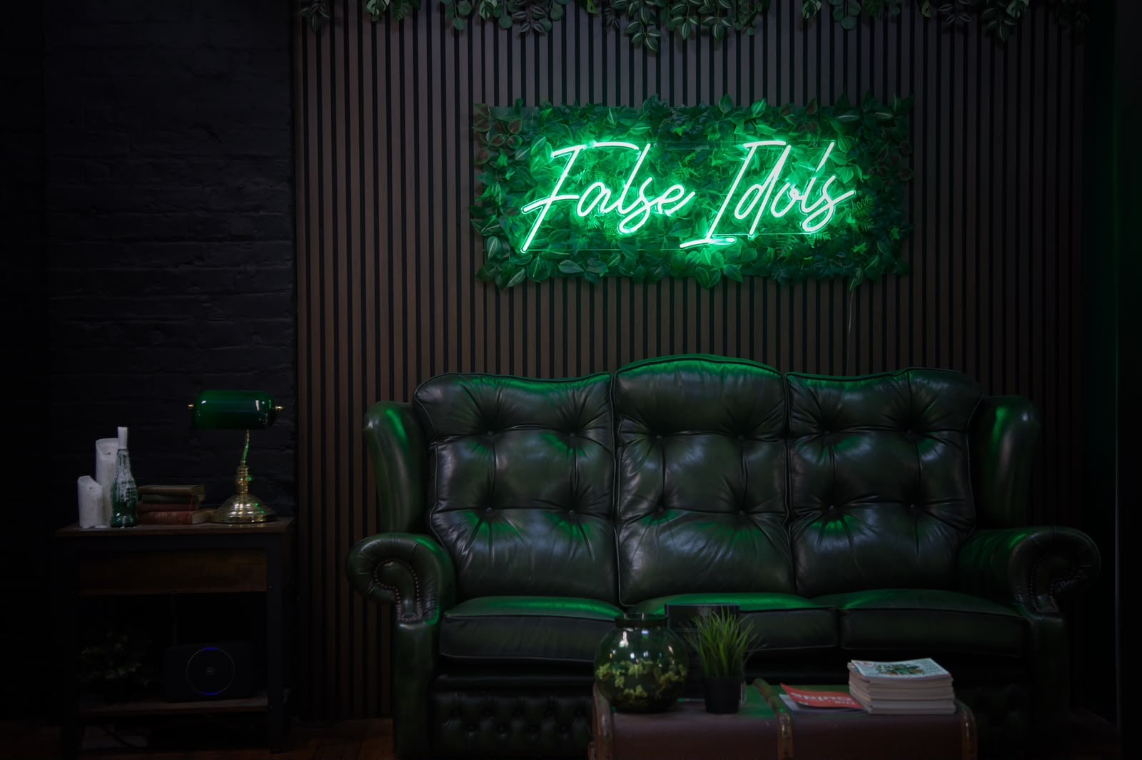 False Idols Tattoo Studio lounge with green leather sofa and neon False Idols sign